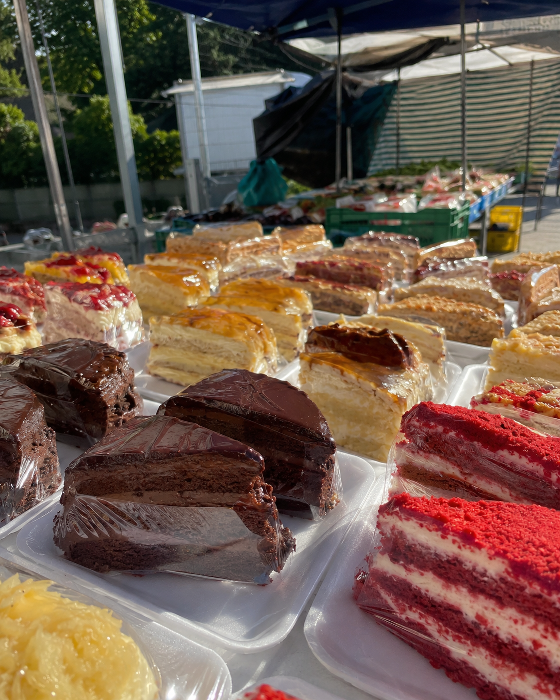 Bancada de feira cheia de fatias de bolo recheado prontas pra venda